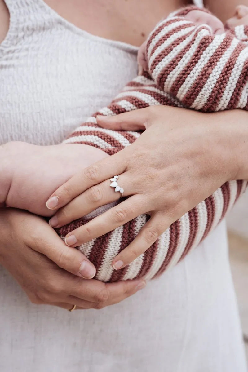 Mother wearing a breastmilk ring holding a baby - breastmilk jewellery